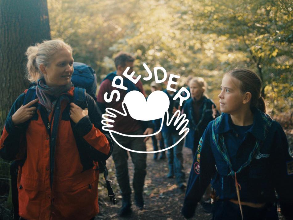 Voksen og spejder på tur. Spejderdagslogo i midten 